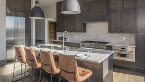 Een moderne keuken met donker houten kastjes, roestvrijstalen apparatuur en een centraal eiland met barstoelen.