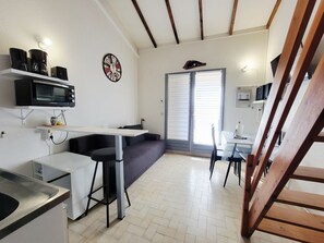 Una cucina compatta con un forno a microonde, una macchina per il caffè e una sveglia appesa al muro.