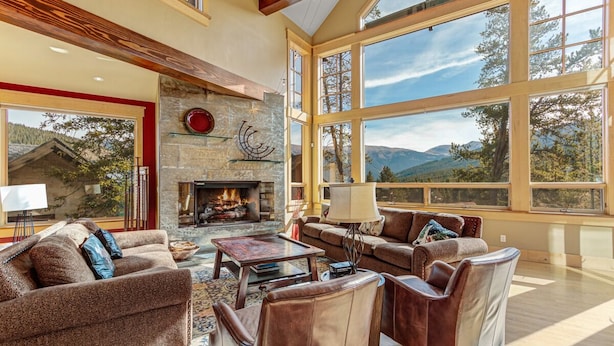A spacious living room with a fireplace, large windows, and a view of the mountains. - Ski-In/Ski-Out House | Hot Tub | Views (Copper Mountain)