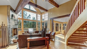 A spacious living room with a fireplace, wooden floors, and a staircase. - Ski-In/Ski-Out House | Hot Tub | Views (Copper Mountain)