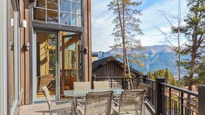 An outdoor patio with a glass table and chairs, overlooking a mountainous landscape. - Ski-In/Ski-Out House | Hot Tub | Views (Copper Mountain)