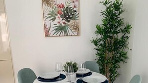 Un coin repas avec une table ronde, quatre chaises bleu clair et une grande plante verte.