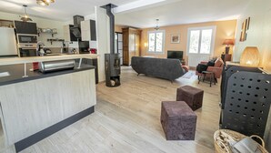 A modern kitchen with a central island, a built-in stove, and a dining area with a sofa and chairs. - Chambres d'hôtes Au Chat Verrier, espace bien-être (Bagneaux-sur-Loing)