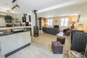 Cocina moderna con isla central, estufa integrada y comedor con sofá y sillas.