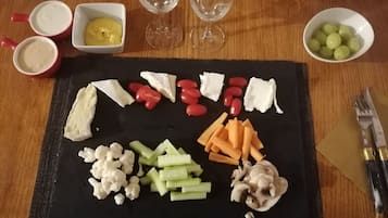 Een charcuterieplank met verschillende kazen, fruit en groenten op een zwarte leisteen.