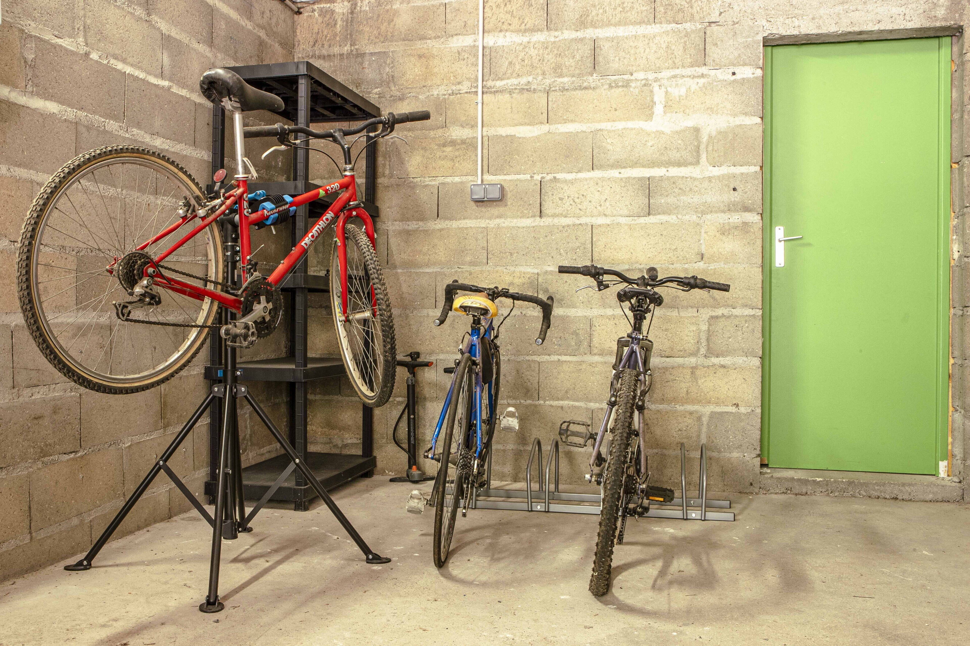 Un support de réparation pour vélos avec deux vélos, une porte verte et un mur en briques.