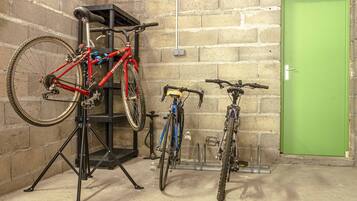 Un support de réparation pour vélos avec deux vélos, une porte verte et un mur en briques.