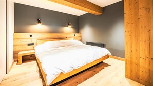 Een moderne slaapkamer met een houten bedframe, een bankje en twee wandlampen.