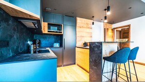Een moderne keuken met een centraal kookeiland, barstoelen en een wand met houten accenten.