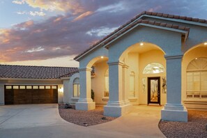 A residential building with a garage, arched entryway, and a tiled roof.