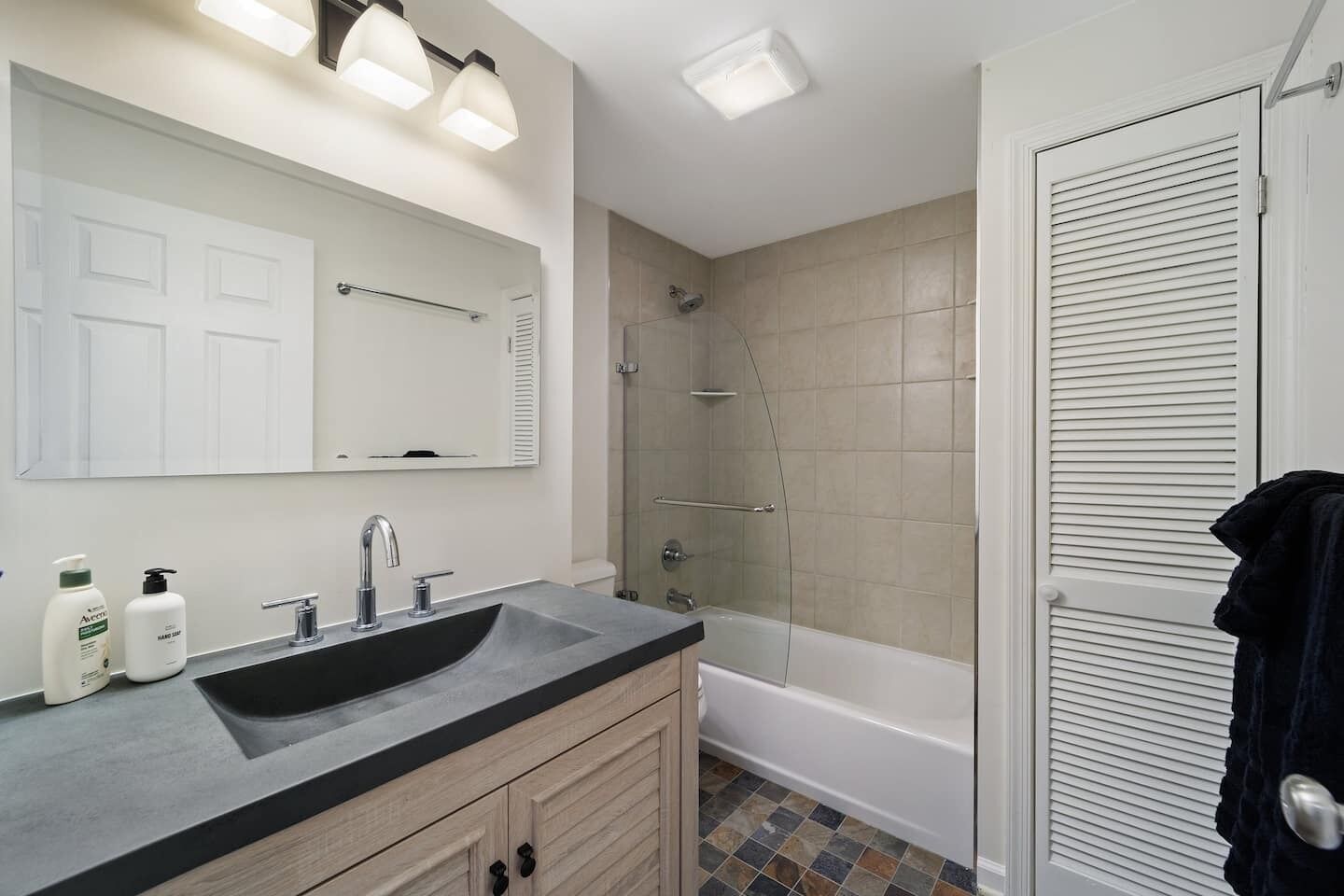 A modern bathroom with a large sink, mirror, and a walk-in shower.