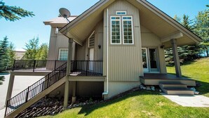 A two-story house with a covered porch, a satellite dish, and a small front yard.