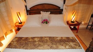 Una cama bien hecha con un cabecero decorativo, dos lámparas de noche y un arreglo floral.