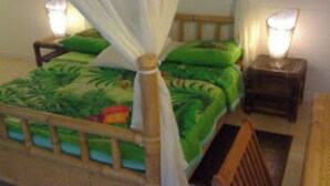Una cama con dosela, ropa de cama verde y dos lámparas de noche.
