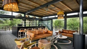 A modern outdoor living area with a wooden ceiling, leather sofas, and a central wood-burning stove. - Mbazo Safaris (Pilanesberg National Park)