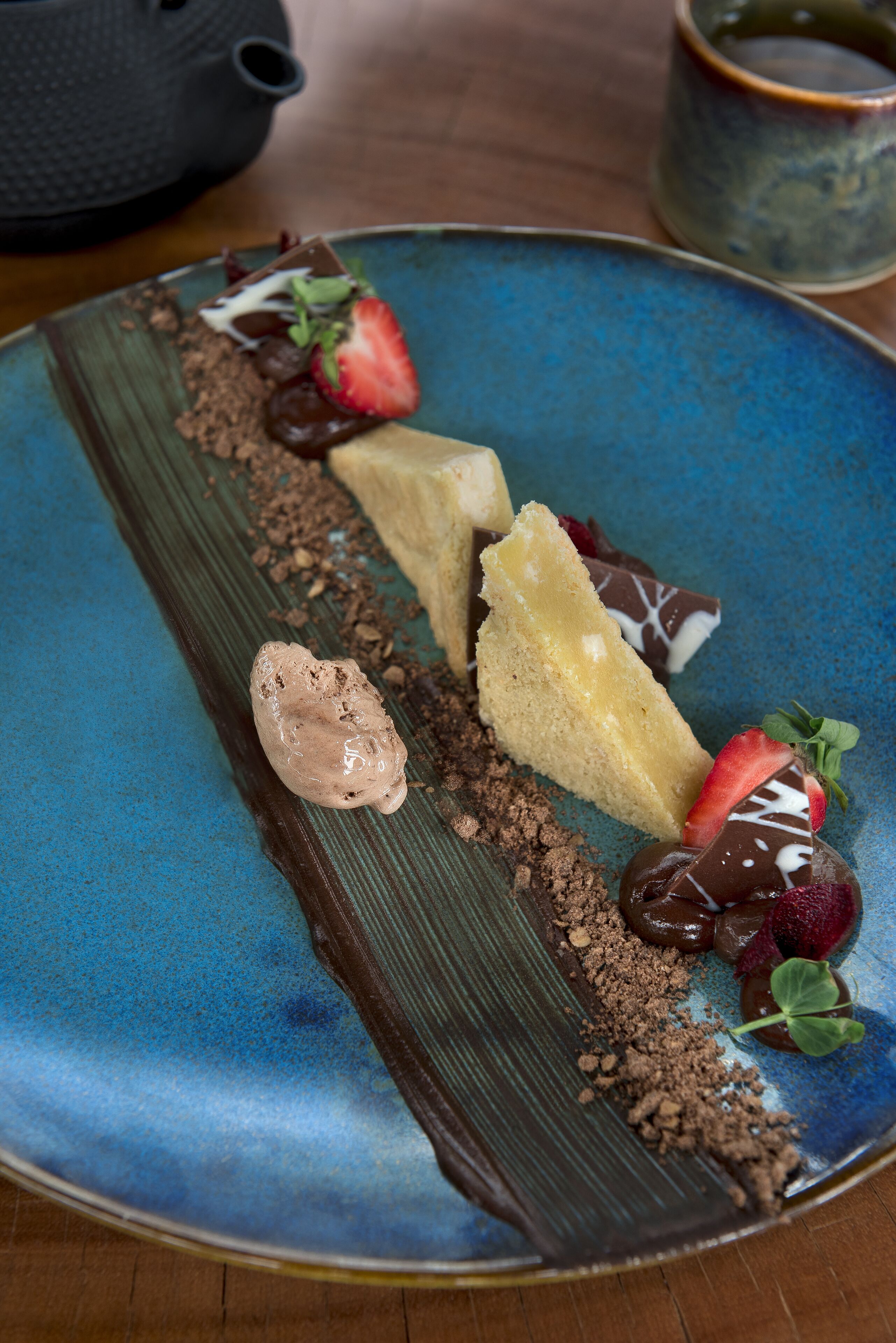 Un plato con postres y trozos de chocolate sobre una vajilla azul.