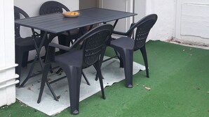 A patio with a table and chairs, a door, and a window with shutters. - 2 Pièces 50m² Ensoleillés + 2 Terrasses BBC (Menton)