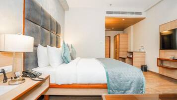 Una habitación de hotel moderna con una cama grande, una mesita de noche con lámpara, un teléfono y un cabecero de madera.