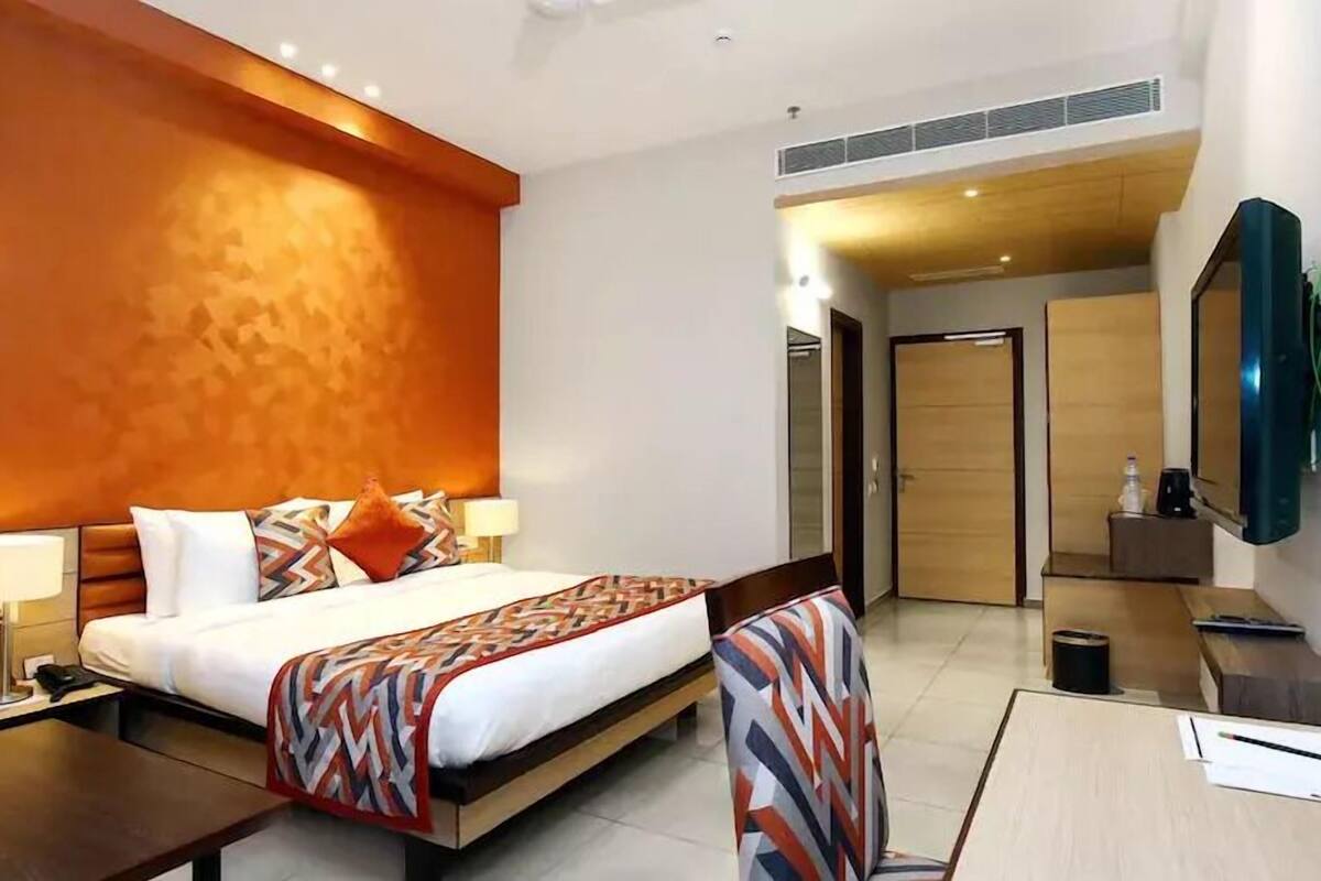Une chambre d’hôtel avec un grand lit, des tables de chevet, un bureau et un téléviseur.