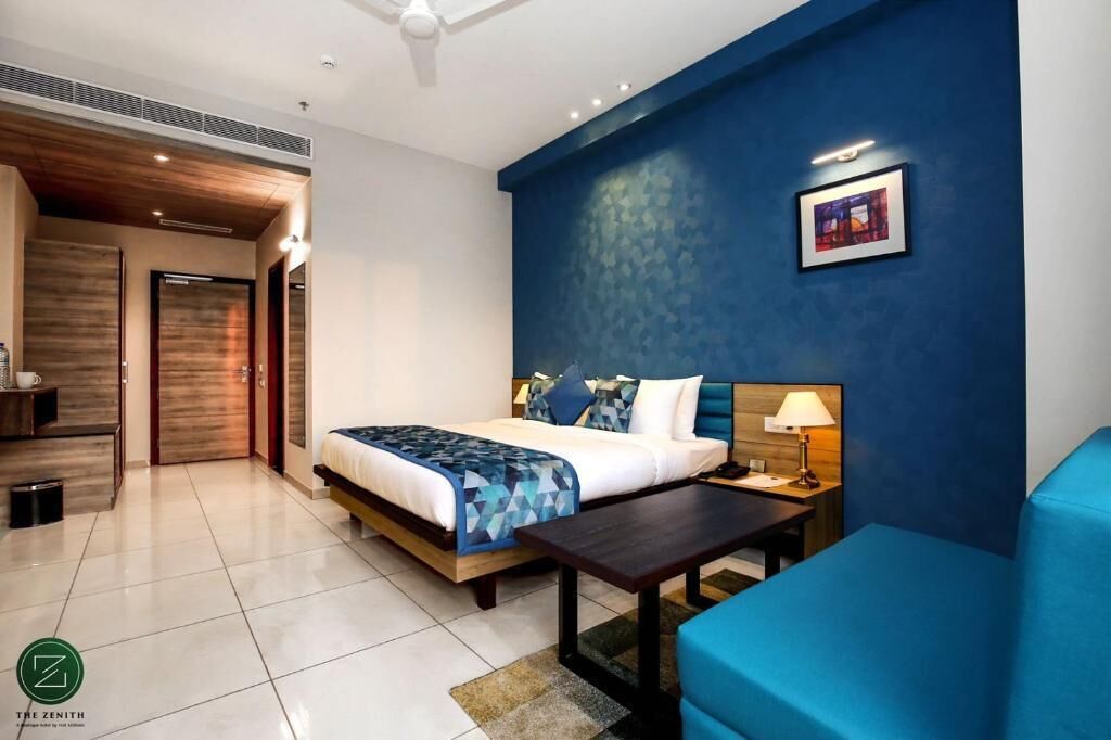 Ein Hotelzimmer mit einem Bett, einem Schreibtisch, einem Stuhl und einer blauen Wand.