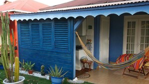 Een blauw huis met een hangmat en stoel buiten.