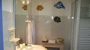 Een badkamer met een wastafel, spiegel en douche.