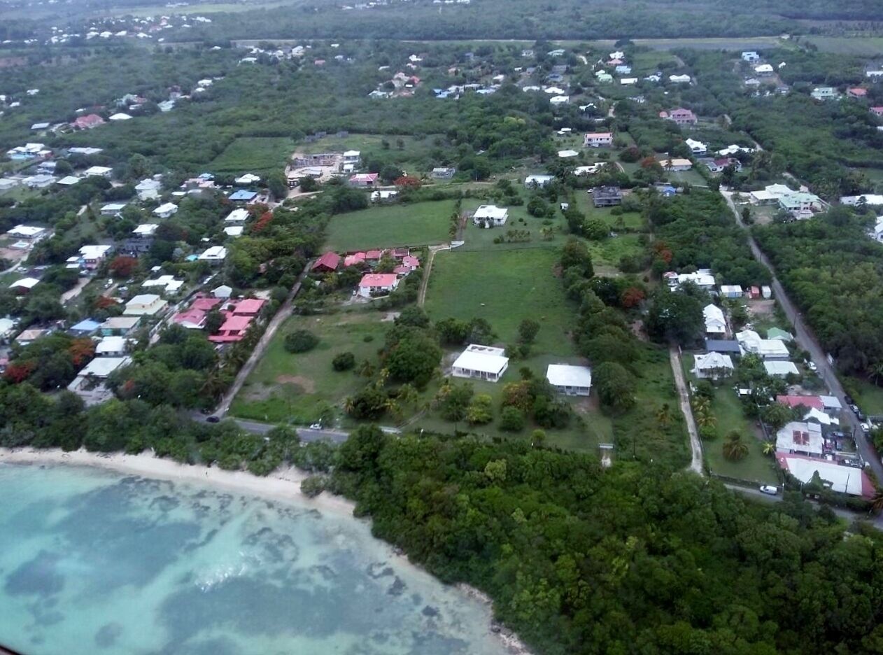 Luchtbeeld van een kustgebied met huizen, een strand en helder uitzicht op de oceaan.