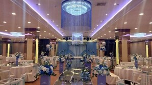 A banquet hall with round tables, a central stage, and a large chandelier. - Cuilinyuan Hotel (Zibo)