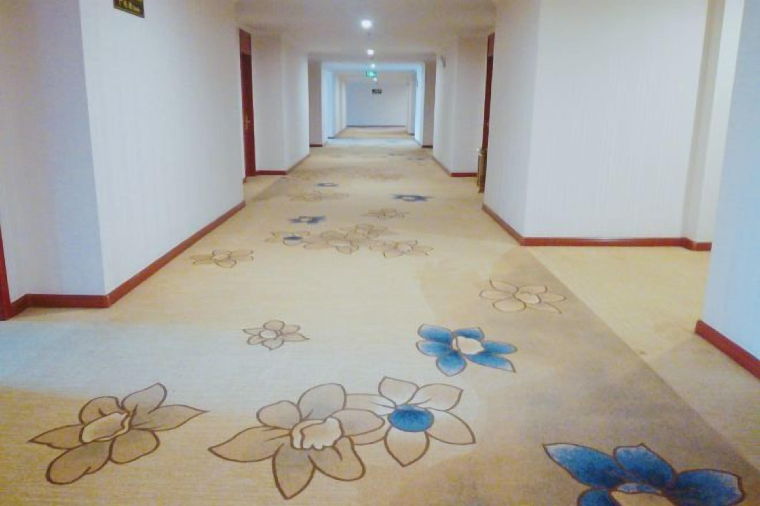 Un pasillo alfombrado con motivos florales y ribete rojo.