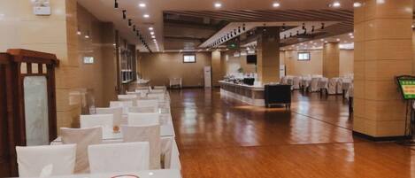 A spacious hall with rows of tables and chairs, a reception area, and a counter.