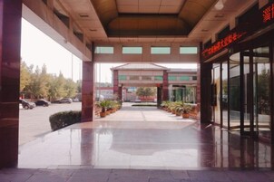 A building entrance with a covered walkway, potted plants, and a glass door entrance.