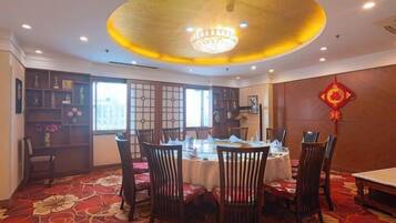 A dining area with a round table, chairs, and a chandelier.