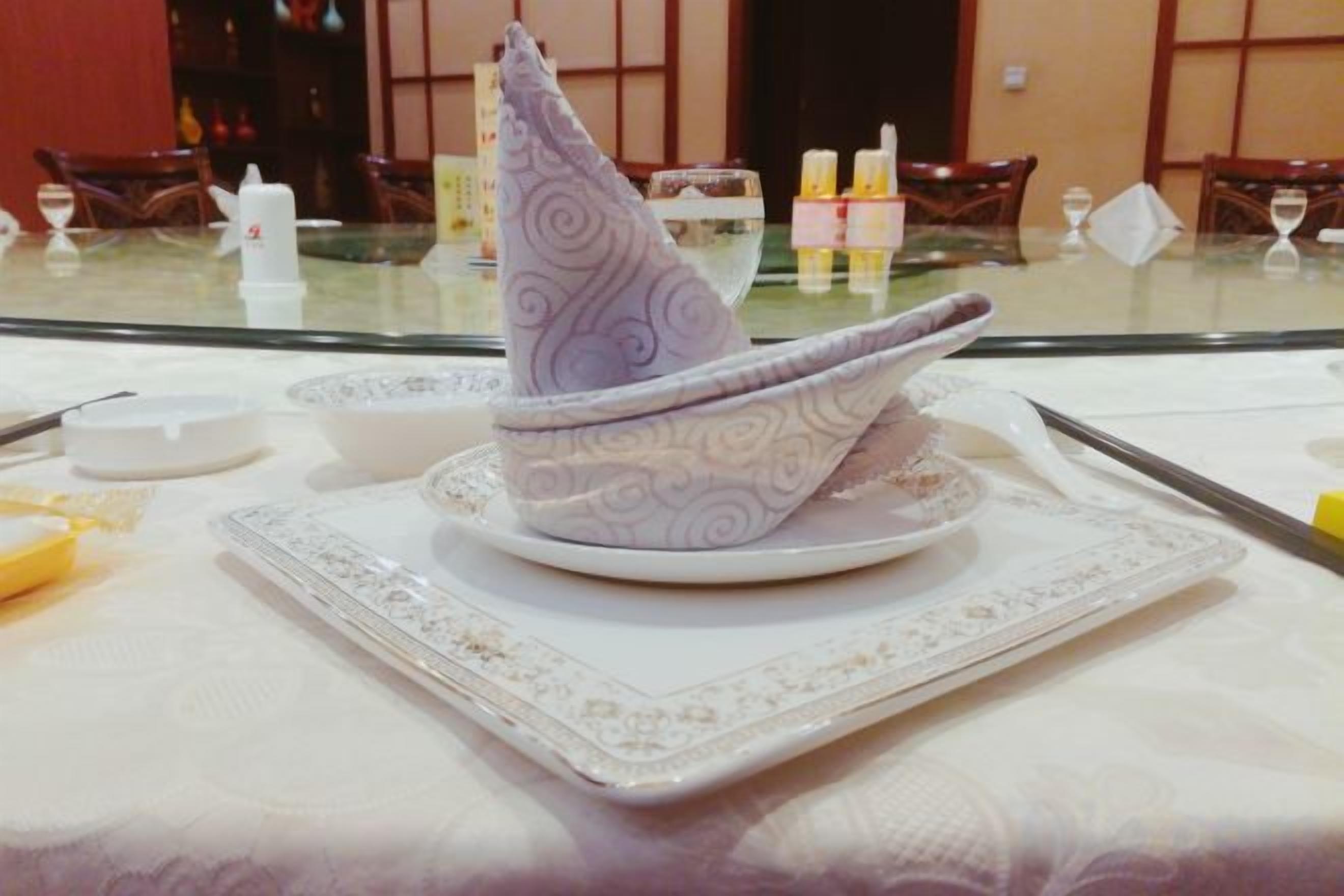 Una mesa con un mantel, un servilleta doblada, un plato y un bol.