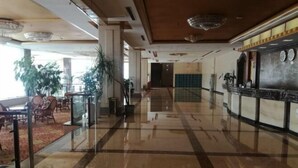 A hotel lobby with a polished marble floor, a reception desk, and a seating area with chairs and tables. - Cuilinyuan Hotel (Zibo)