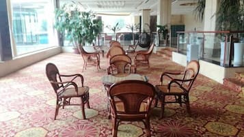 Un vestíbulo amplio con alfombra estampada, muebles de mimbre y ventanas grandes.