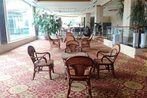A spacious lobby with a patterned carpet, wicker furniture, and large windows. - Cuilinyuan Hotel (Zibo)