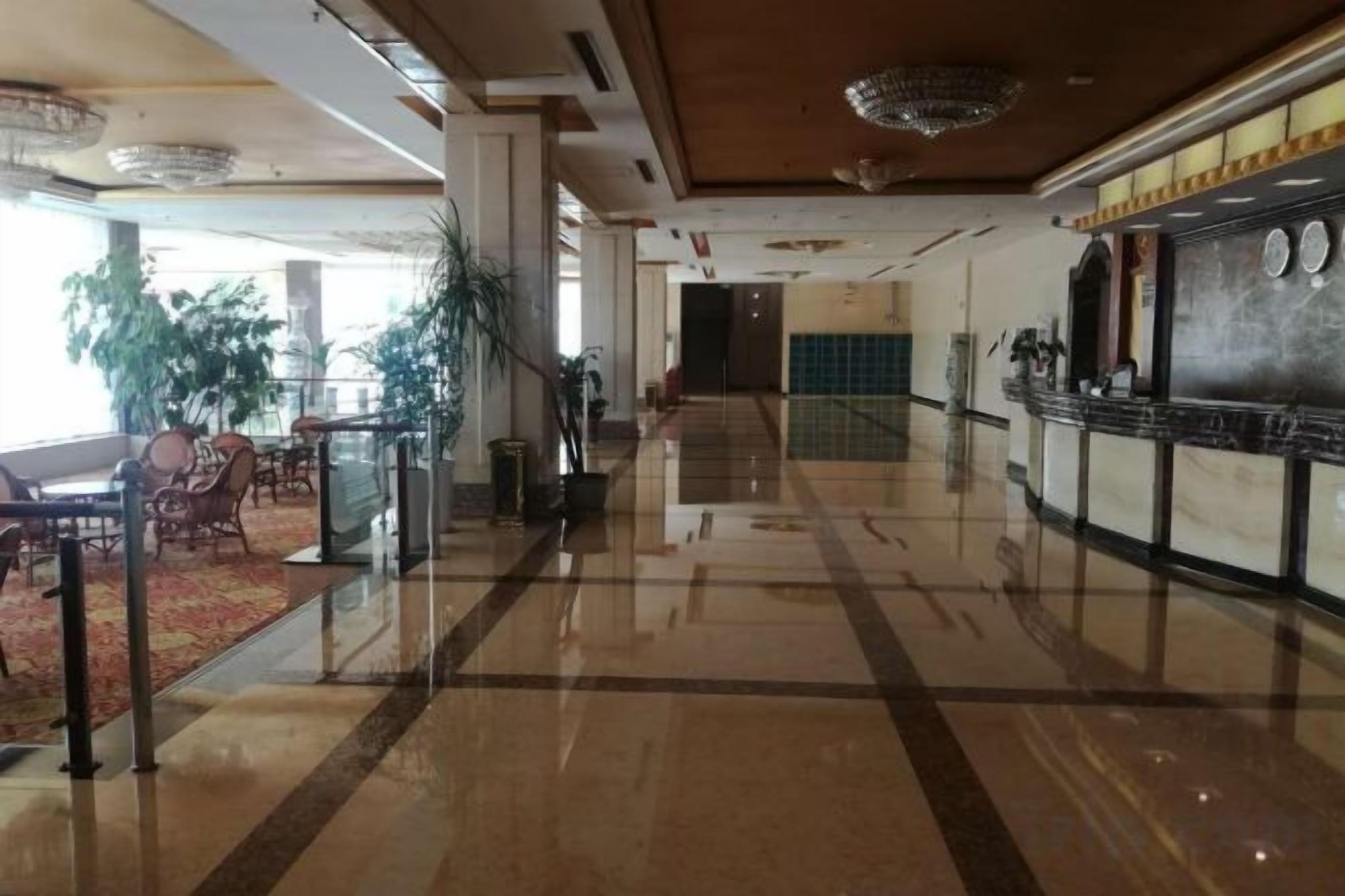 A hotel lobby with a polished floor, seating area, and a reception desk.