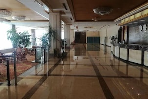 Um saguão de hotel com piso lustroso, área de estar e balcão de recepção.
