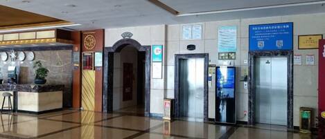 A hotel lobby with a reception desk, elevators, and a clear floor plan.