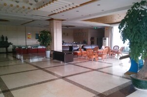 Un hall amplio con mostrador de recepción, zona de estar y grandes plantas en macetas.