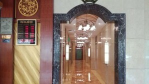 A hotel lobby with a marble floor, a reception desk, and a digital display board. - Cuilinyuan Hotel (Zibo)