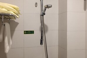 A shower area with a chrome showerhead and a towel rack with a yellow towel. - Cuilinyuan Hotel (Zibo)