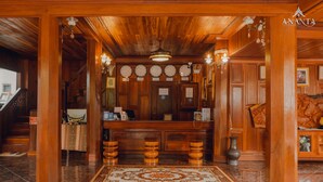 Un espace d’accueil en bois, doté d’un sol en marbre, d’un comptoir de réception et d’un escalier.