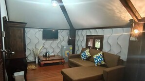 Un salon chaleureux avec un canapé marron, un plancher en bois, un téléviseur et un panneau décoratif mural.