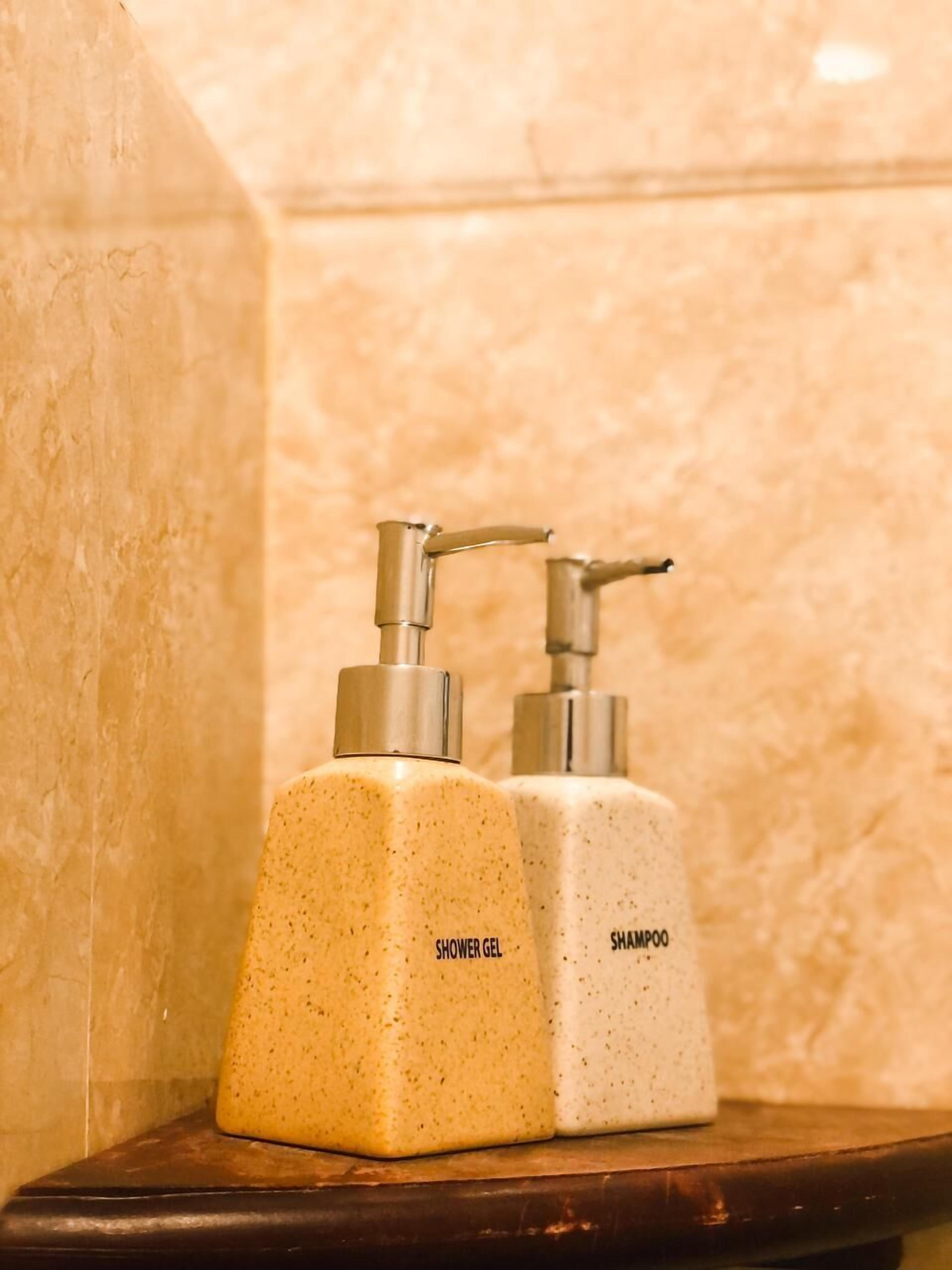 Two toiletry bottles labeled 'shower gel' and 'shampoo' on a wooden shelf.