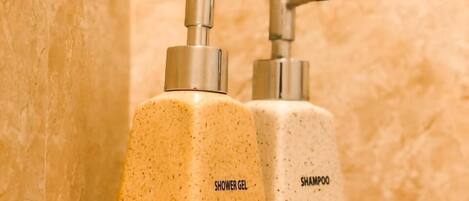 Two toiletry bottles labeled 'shower gel' and 'shampoo' on a wooden shelf.