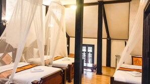 Une chambre avec quatre lits, chacun doté d’un baldaquin. La chambre est dotée d’un plancher en bois et d’un plafond en pente.