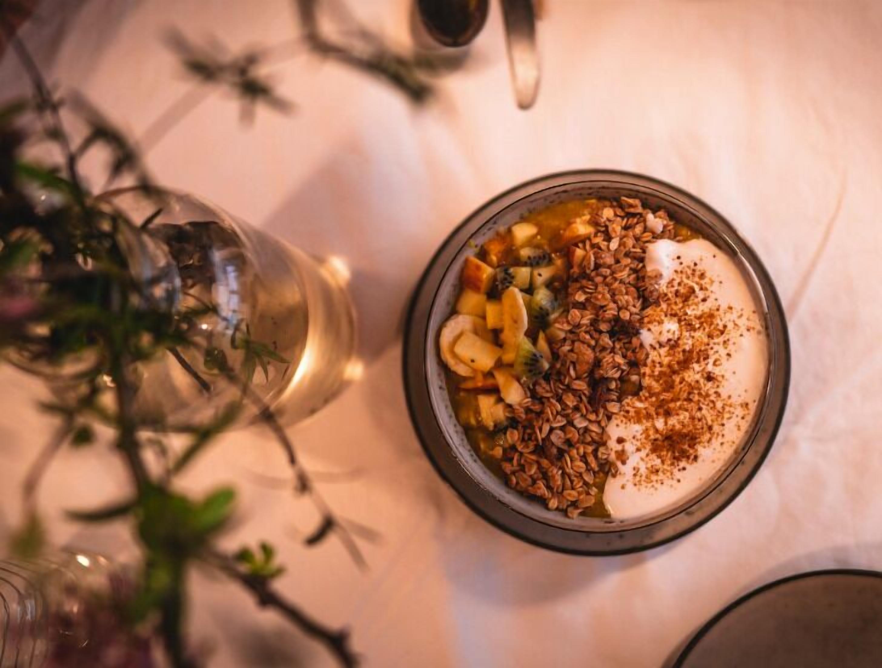 A bowl of yogurt topped with granola, fruit, and a sprinkle of cinnamon.