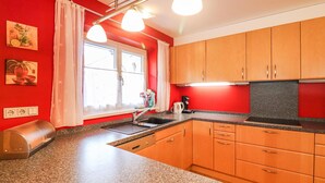 A kitchen with wooden cabinets, a granite countertop, a window with curtains, and a coffee maker.