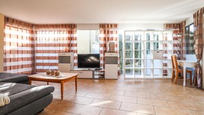 A living room with a sofa, TV, and a dining area with a table and chairs.